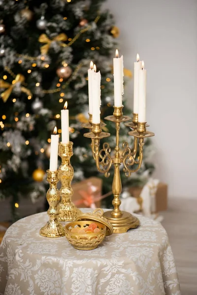 Свічки та цукерки на столі Нового року. Різдвяна ялинка з ліхтарями на фоні — стокове фото