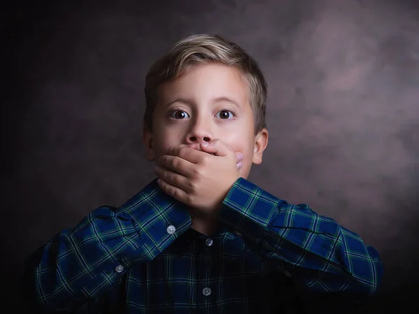 Portrét roztomilý chlapeček zavřel ústa rukou, studio zastřelil — Stock fotografie