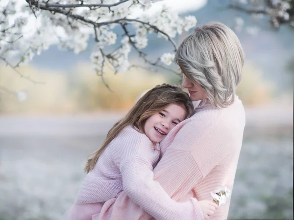 Portret van de moeder en dochter zachtjes in de tuin met bloeiende almendra omhelzen — Stockfoto