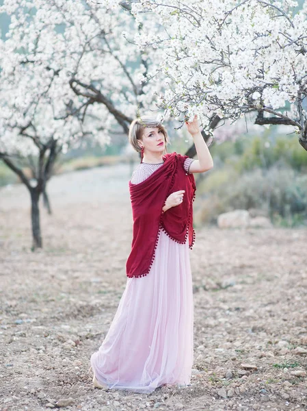 Bahçelerde çiçek açması badem güzel uzun elbiseli bir genç kadın — Stok fotoğraf