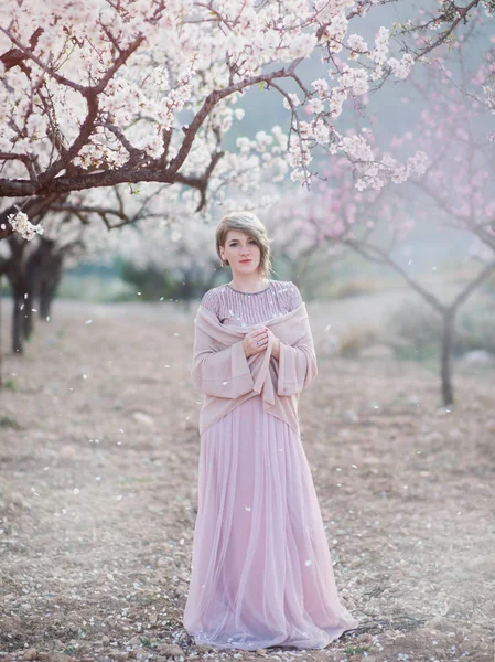 Jeune femme dans les jardins d'amandes en fleurs dans une belle robe longue — Photo