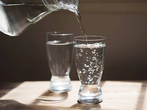 Un vaso de agua sobre una mesa de madera —  Fotos de Stock