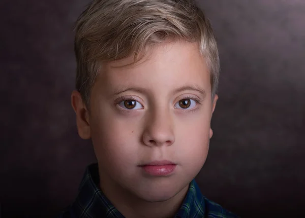 Portret van een schattige blonde tiener jongen gekleed in een plaid shirt. — Stockfoto