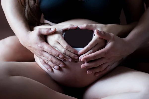 Mãos de membros da família segurando uma barriga de mulher grávida . — Fotografia de Stock