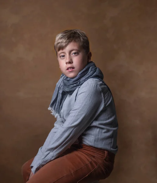 Retrato de um menino em um cachecol em um fundo escuro . — Fotografia de Stock