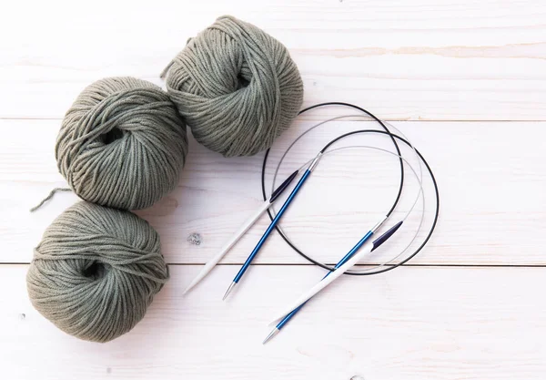 Threads for knitting with spokes on a light wooden background. — Stock Photo, Image