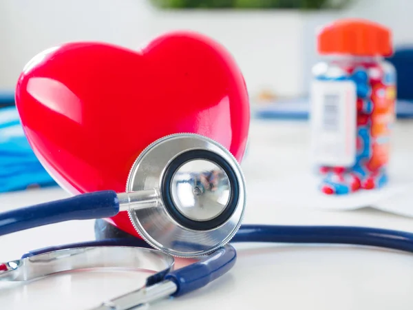 Corazón rojo y estetoscopio en la mesa del médico — Foto de Stock