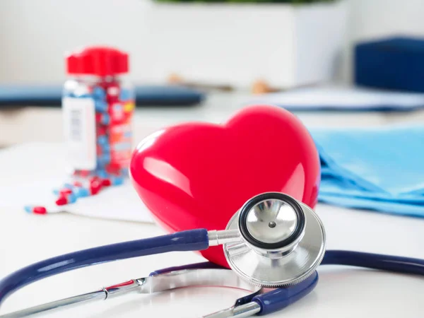 Corazón rojo y estetoscopio en la mesa del médico — Foto de Stock