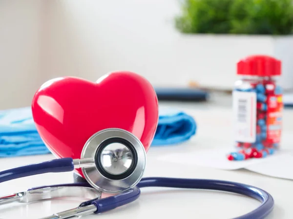 Corazón rojo y estetoscopio en la mesa del médico —  Fotos de Stock