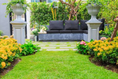 Taş bir banka bir çiçek bahçesinde çay seti.