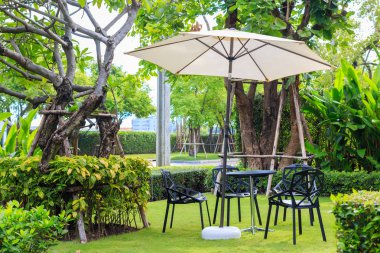 GA çimenlerin üzerinde beyaz şemsiye altında siyah masa sandalye