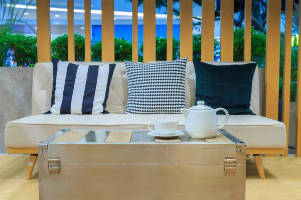 Tres almohadas en el sofá de tela y el juego de té en la mesa hacen de — Foto de Stock