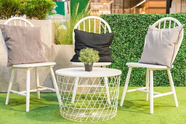 Pillows on a white wooden chairs and a white table on artificial — Stock Photo, Image