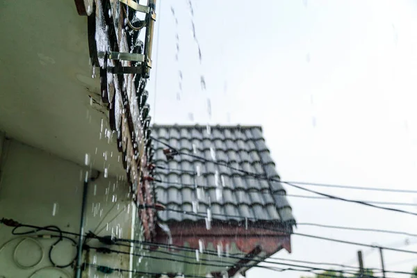 Chuva água caindo do telhado velho quando a chuva caindo . — Fotografia de Stock