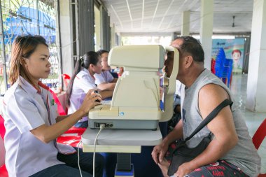 Yetişkin adamın gözünün içine topluluk serv inceleyerek kadın Optictian