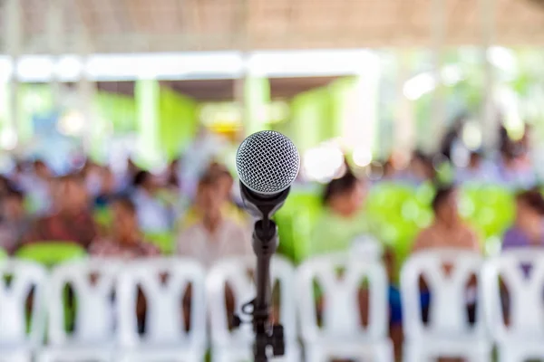 Un microfono sul supporto del microfono con un popolo seduto su una sedia — Foto Stock