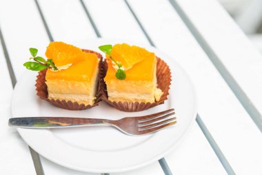 Onrange kek bir çatal Beyaz ahşap masa ile beyaz disk üzerinde.