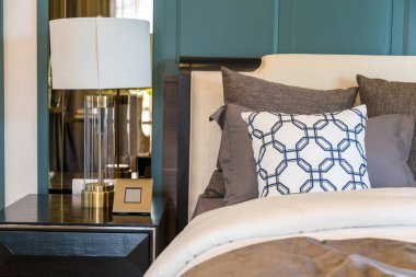 Yatakta kahverengi battaniye ile kahverengi bir yastık ve lüks lambası woo