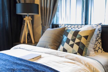 Birçok yastık ve battaniye beyaz ve kahverengi bir kitapla yatakta w