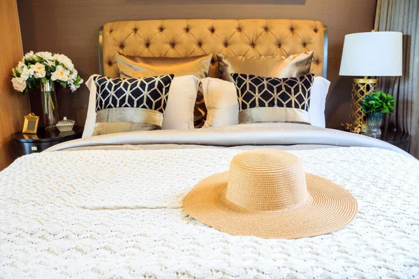 An interior bedroom design with lady hat on luxury bed.