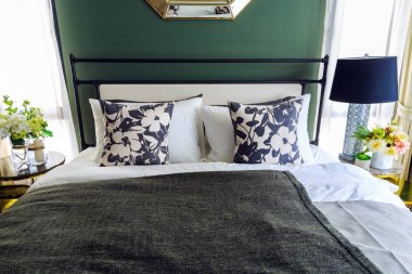 Bir çiçek desenli yastıklar yatakta siyah battaniye ve lam