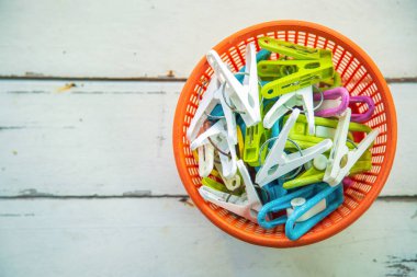 Üst manzara turuncu plastik sepette eski renkli bir mandal beyaz ahşap zemin üzerinde fotokopi için boş sol taraf.