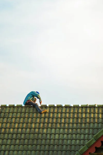 A minimalist picture construction worker is repairing the roof against sky background