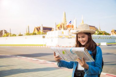 Kotlu ceket ve hasır şapkalı güzel Asyalı kadın Wat Phra Kaew 'da seyahat ederken gülümseyerek elindeki haritaya bakarken arkaplan bulanıklaşmıştı. Kopya alanı için sol taraf boştu..