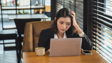 Bilgisayarın önünde oturan Asyalı genç iş kadınının portresini yakından çek, bir seçim yap ve başını iş yerinde tut..