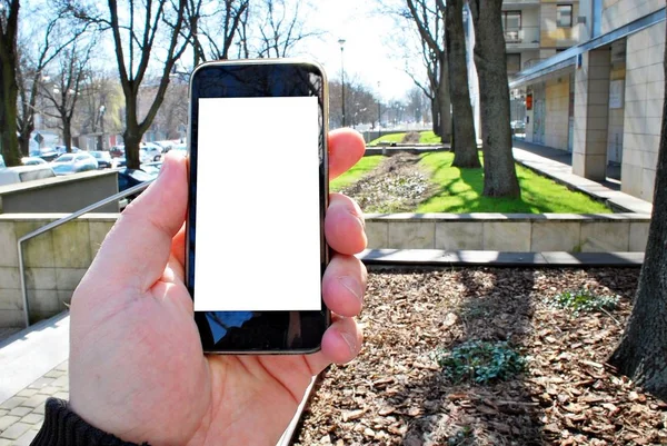 Hand innehav smartphone. Staden i bakgrunden — Stockfoto