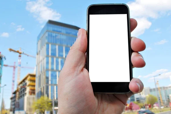 Hand holding smartphone. City in the background — Stock Photo, Image