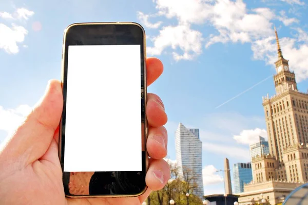 Hand holding smartphone. City in the background — Stock Photo, Image