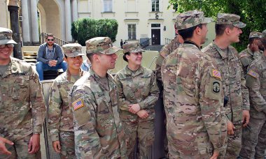 Amerikalı bir asker üniformalı ve sivil adam el sıkışan takım elbiseli