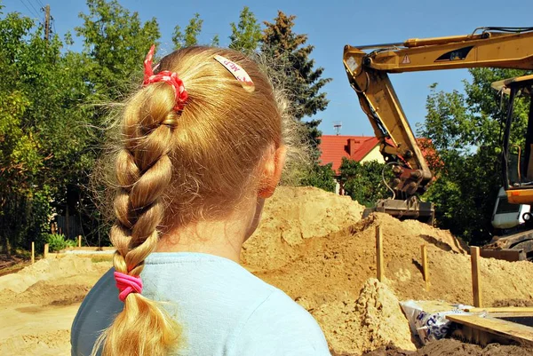 Menina observando o trabalho de uma máquina de construção — Fotografia de Stock