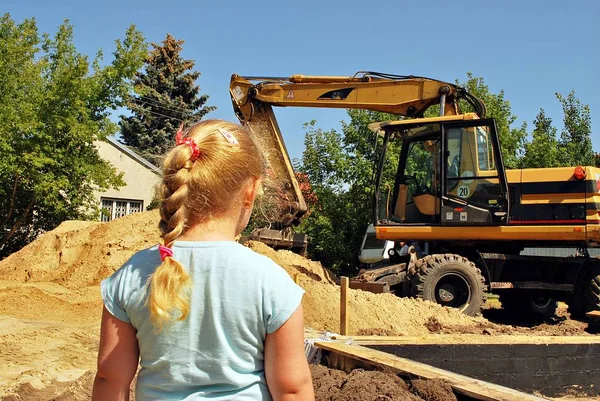 Menina observando o trabalho de uma máquina de construção — Fotografia de Stock