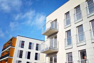 Mavi gökyüzü olan güneşli bir günde modern apartman binaları. Modern bir apartmanın cephesi