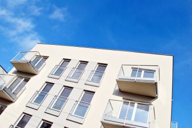 Mavi gökyüzü olan güneşli bir günde modern apartman binaları. Modern bir apartmanın cephesi