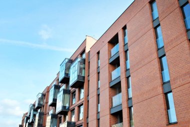 Mavi gökyüzü olan güneşli bir günde modern apartman binaları. Modern bir apartmanın cephesi