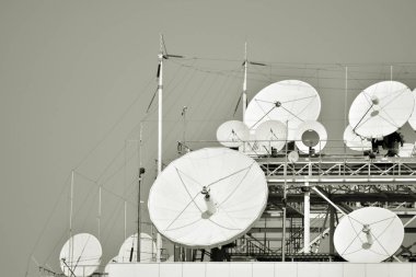 Satellite Communications Dishes on top of TV Station. Black and white. clipart