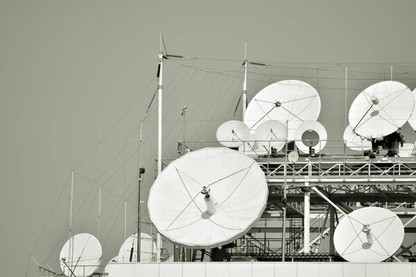 Satellite Communications Dishes on top of TV Station. Black and white.