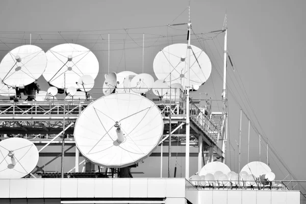 Satellite Communications Dishes on top of TV Station. Black and white.