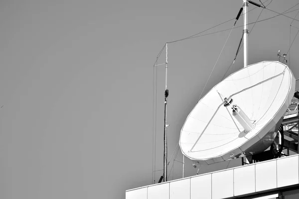 Satellite Communications Dishes on top of TV Station. Black and white.