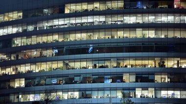 Ofis binalarının pencereleri gece aydınlandı. Şehir merkezinde yansıması olan cam mimari cephe tasarımı ile ışıklandırma.