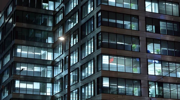 Pattern of office buildings windows illuminated at night. Lighting with Glass architecture facade design with reflection in urban city.