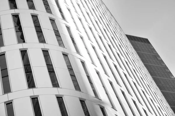 Curtain wall made of toned glass and steel constructions under sky. A fragment of a building. Black and white.