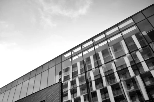 Curtain wall made of toned glass and steel constructions under sky. A fragment of a building. Black and white.