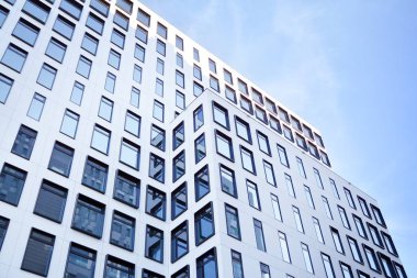 Modern Avrupa binası. Mavi gökyüzüne karşı birçok penceresi olan beyaz bir bina. Soyut mimari, modern şehir geometrisinin bir parçası.