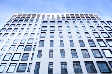 Modern Avrupa binası. Mavi gökyüzüne karşı birçok penceresi olan beyaz bir bina. Soyut mimari, modern şehir geometrisinin bir parçası.