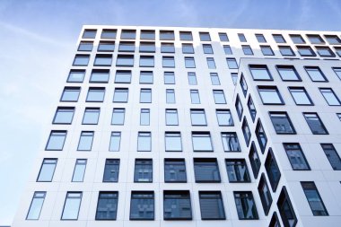 Modern Avrupa binası. Mavi gökyüzüne karşı birçok penceresi olan beyaz bir bina. Soyut mimari, modern şehir geometrisinin bir parçası.