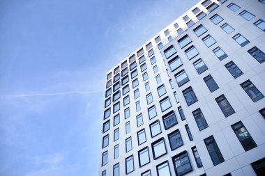 Modern Avrupa binası. Mavi gökyüzüne karşı birçok penceresi olan beyaz bir bina. Soyut mimari, modern şehir geometrisinin bir parçası.